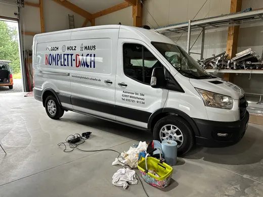 Ein ANKERHELD Lieferwagen steht in einer Halle, davor liegen Putzutensilien wie Eimer, Tücher und Reinigungsmittel auf dem Boden. © Kellermanns