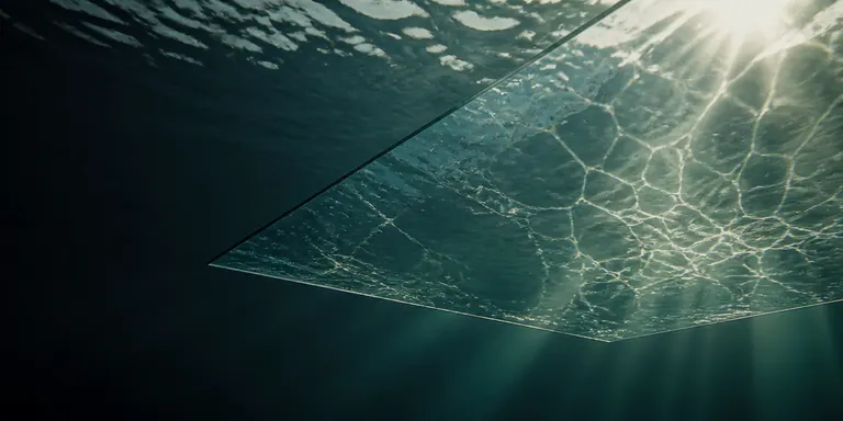 Sonnenlicht faellt durch die Wasseroberflaeche auf eine Glasflaeche