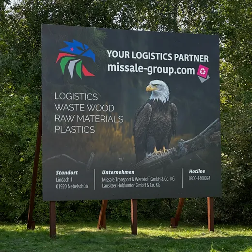 Werbeplakat im Freien mit einem Adler, Text zu Logistikdienstleistungen und dem Markennamen ANKERHELD, Bäume im Hintergrund. © Kellermanns
