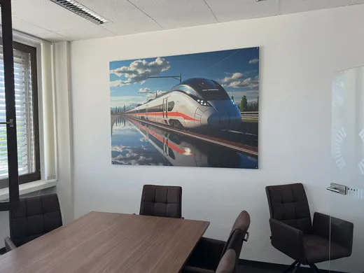 Besprechungsraum mit Tisch und Stühlen, an der Wand ein großes Bild eines Zuges. Moderner Look, gestaltet von