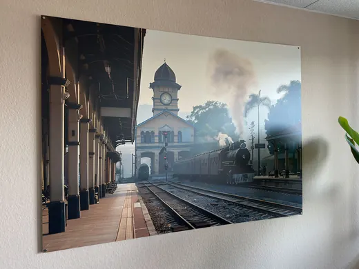 Ein großes Wandbild zeigt einen Bahnhof mit Dampflok, Gleisen und Uhrturm, umgeben von Dampf und Palmen